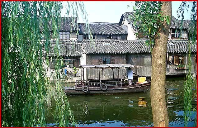 2002-27-V38  - Empty tourist boat passing - - - - Still no other people in the street life of the restored section of Wuzhen - - - But don't worry - there is a street with restaurants and souvenir shops, - everything a tourist can ask for, - but not really everything a traveller wants - - -