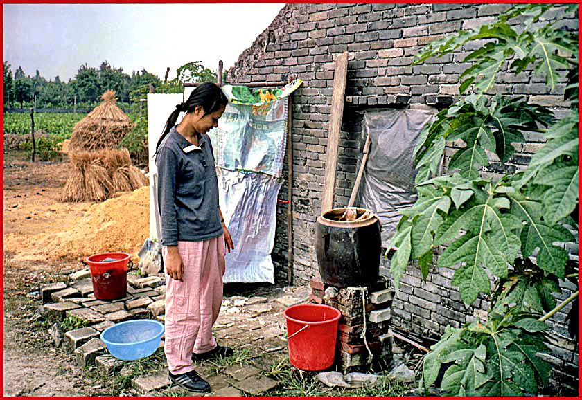 2003-14-019  - Kit Yu checking outthe farmers water cleaning device - - - - don't ask me how it works, but it is obviously some sort of filtering device that cleans the Pearl River water, so that it can be used for cooking and drinking, which is otherwise not possible due to the heavy pollution of the Pearl River - - - (Photo- and copyright:  Karsten Petersen)